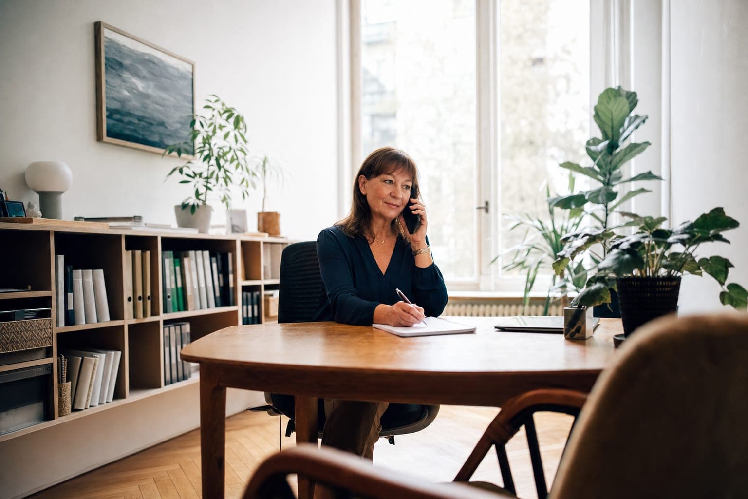 Recruiterin im Telefonat mit Notizblock am Schreibtisch